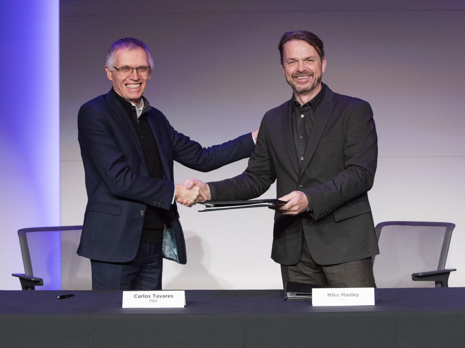 Chairman of the Managing Board of Groupe PSA Carlos Tavares (left) and FCA CEO Mike Manley (right) share a congratulatory handshake after signing the historic combination agreement